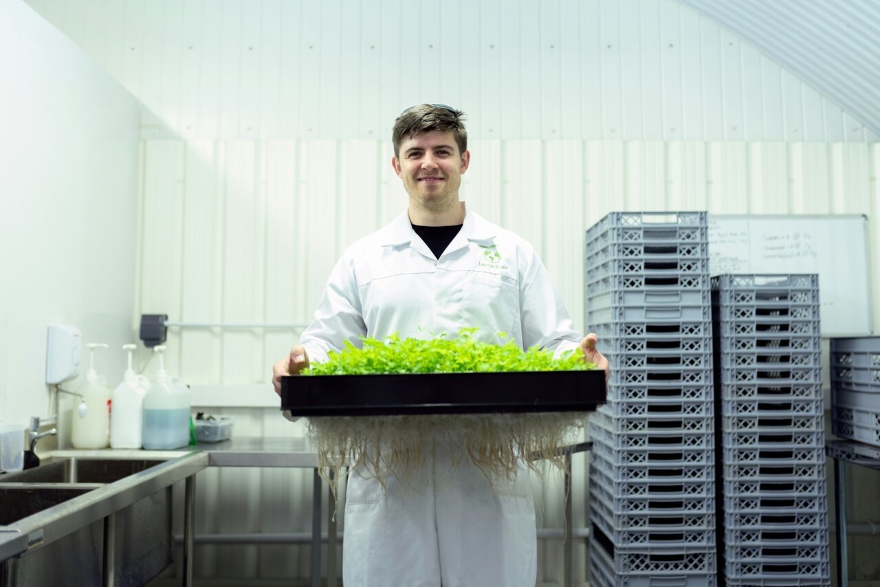 Researcher in a lab coat holding a tray of fresh botanicals