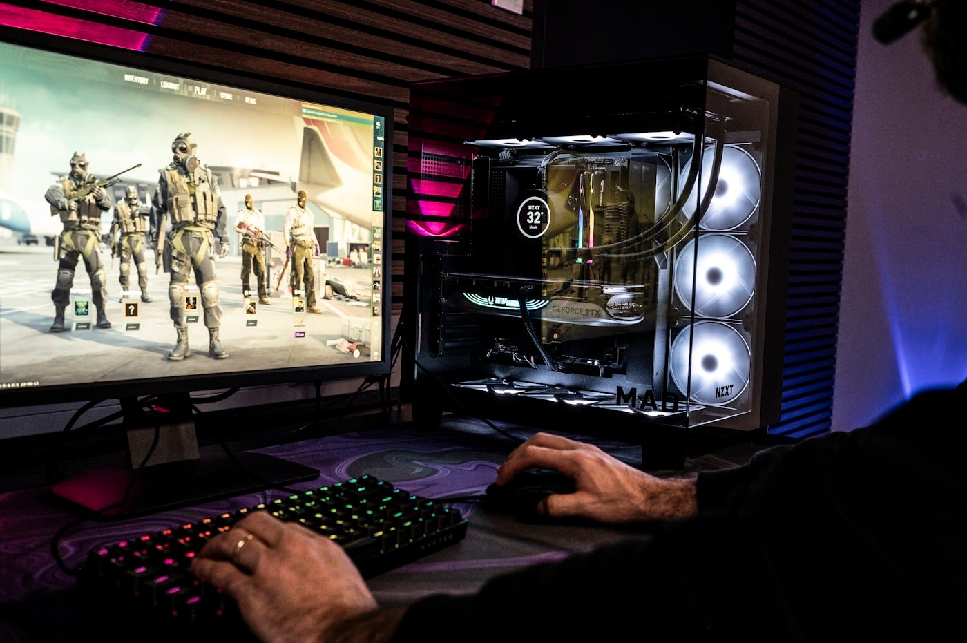 A gamer focused at a PC setup with headset and monitors